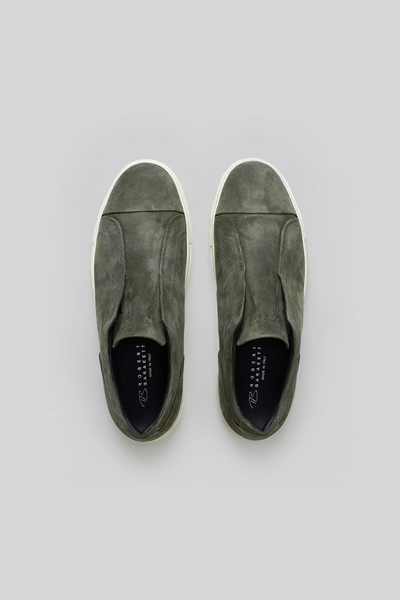 The Robert Barakett Catro Suede Sneaker by Robert Barakett is an olive green Italian suede slip-on with white soles and a cushioned insole, shown from above on a plain grey background.