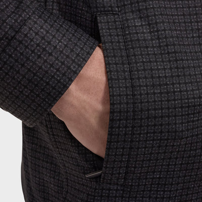 Close-up of a person’s hand partially inside the pocket of a dark gray micro checkered Bugatchi jacket, layered over the Bugatchi Micro Check Knit Shirt (style KF2313K93), against a plain background.