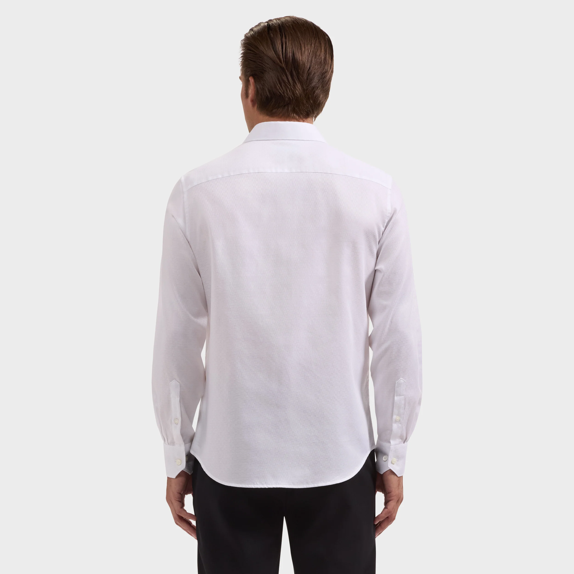 A man is shown from the back against a plain light background, wearing a Bugatchi Julian Tonal Geometric Jacquard Shirt (KS4001L3S) in white and black pants.