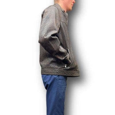 A person in a brown Missani Big & Tall Leather Jacket 394167 and blue pants stands sideways with hands in their jacket pockets against a white background.