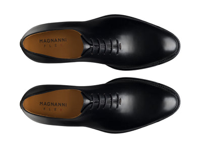 A pair of black calfskin leather Magnanni Hawkins Wholecut Oxford dress shoes with closed lacing, viewed from above, featuring the Magnanni brand on the insoles.