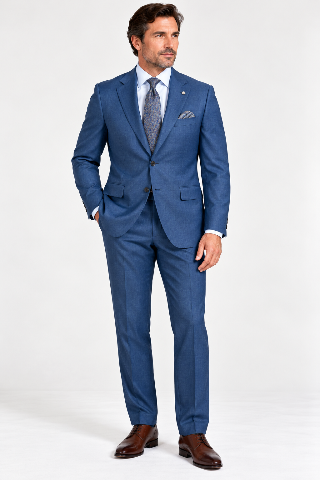 A man wearing a Jack Victor Napoli Suit - Lagoon 3262019, light blue dress shirt, patterned tie, pocket square, and brown leather dress shoes.