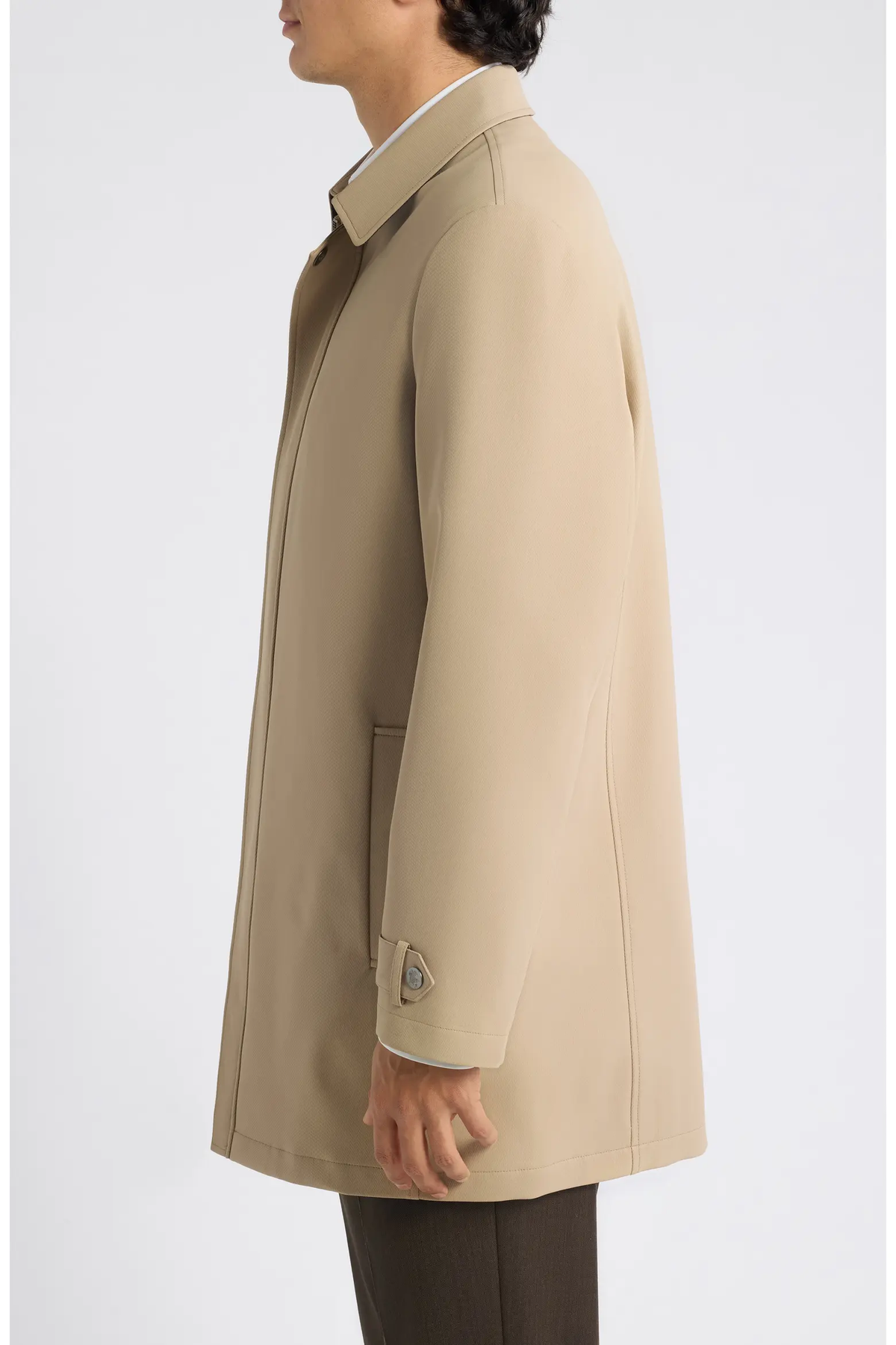 Side profile of a person wearing a tan, mid-length Hart Schaffner Marx Milo Waterproof All-Weather Jacket with a collared neckline and buttoned cuffs.