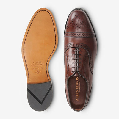 A pair of Allen Edmonds Strand brown calfskin oxfords, one viewed from the top and the other showing the tan leather sole with engraved Allen Edmonds branding.