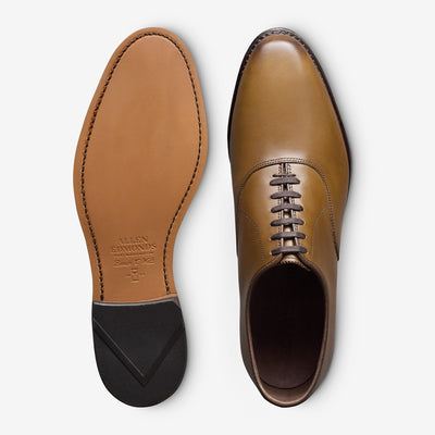 The Allen Edmonds Carlyle is a brown handcrafted leather Oxford dress shoe, shown from the top and sole, featuring closed lacing and a stitched branded leather outsole.