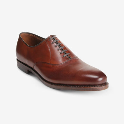 The Allen Edmonds Carlyle by Allen Edmonds is a handcrafted brown oxford dress shoe with closed lacing, low heel, and polished premium leather, featuring bench welt construction, shown on a white background.