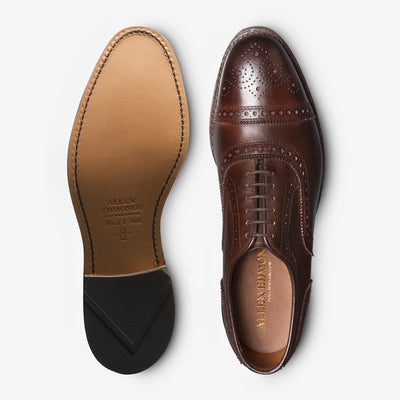 A pair of Allen Edmonds Strand brown calfskin oxford dress shoes—one shows the elegant brogue-detailed top, while the other reveals the branded leather sole.