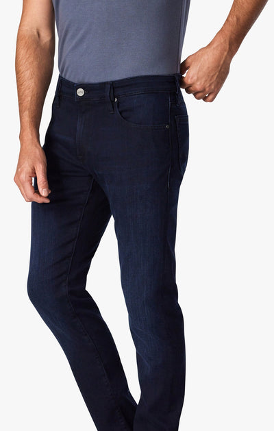 A person wears the 34 Heritage Ink Urban jeans by 34 Heritage, styled with a grey shirt and one hand in their pocket, standing against a plain white background.