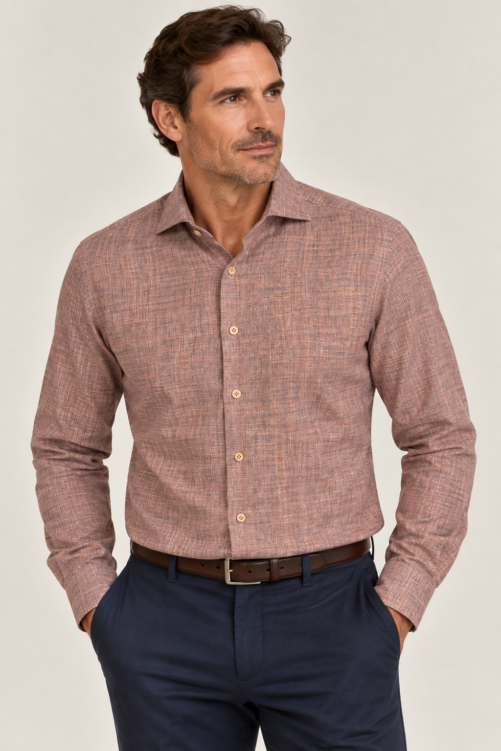 A man wears the Elite Serica Elite Textured Print Sport Shirt EX2674150—a long-sleeve, button-up brown sport shirt—tucked into navy pants with a brown belt. He stands with his hands in his pockets, looking to the side against a plain background.