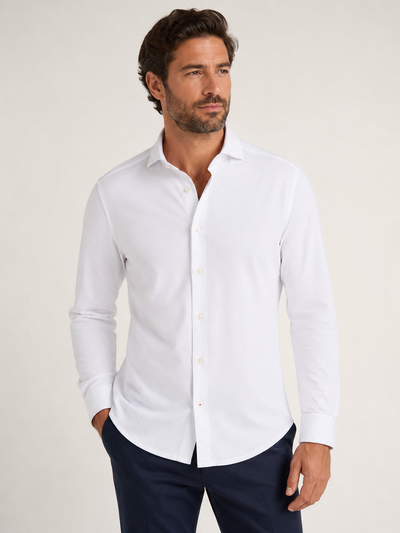 A man stands against a plain background wearing the Stone Rose ORIGIN - Long Sleeve T-Series Sport Shirt paired with dark trousers, looking to his right with one hand in his pocket.