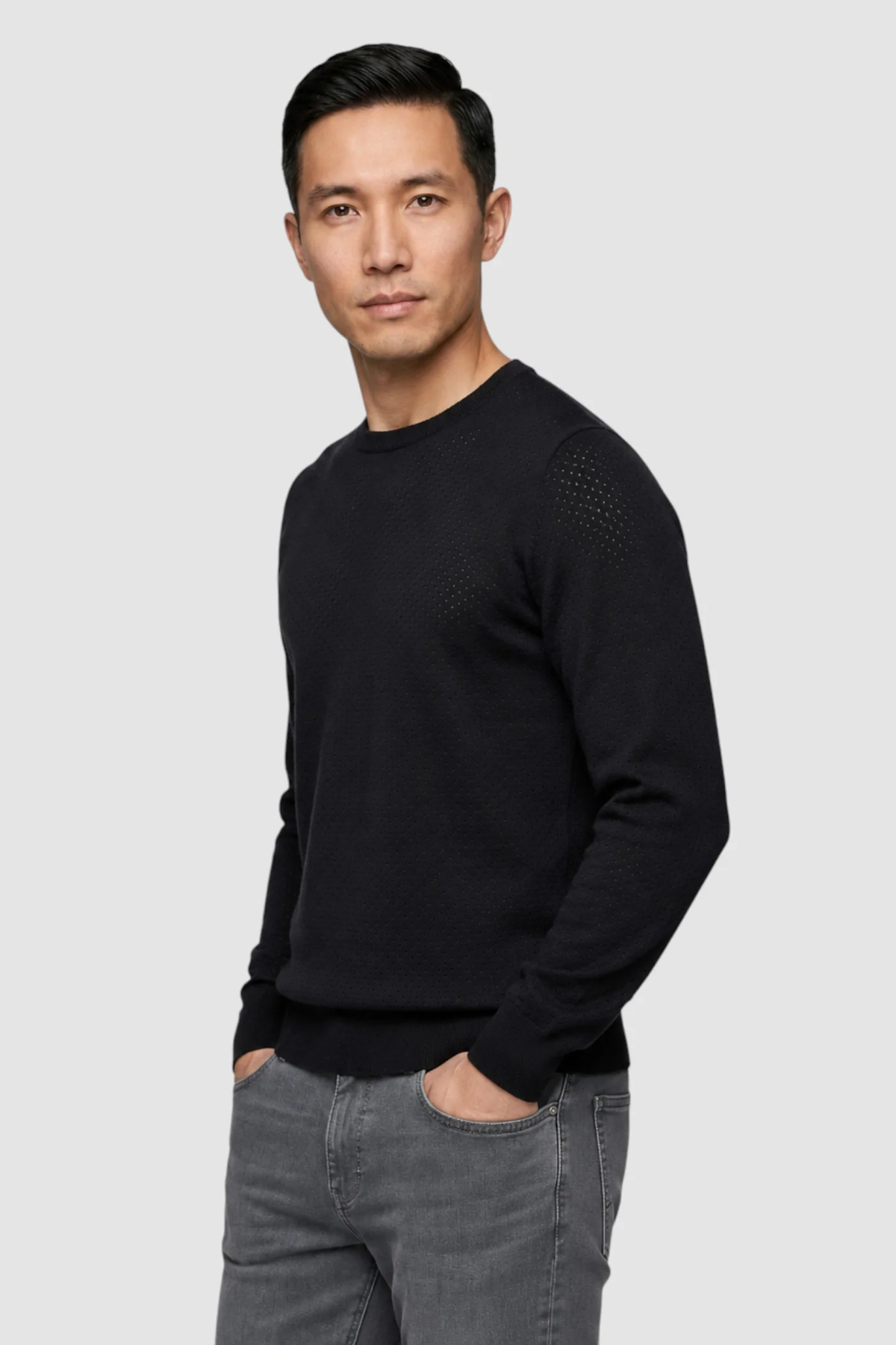A man wearing the Garnet Upton Merino Ribbed Crewneck Sweater (style 2622002) by Garnet and gray jeans stands against a plain light gray background with his left hand in his pocket, looking straight at the camera.