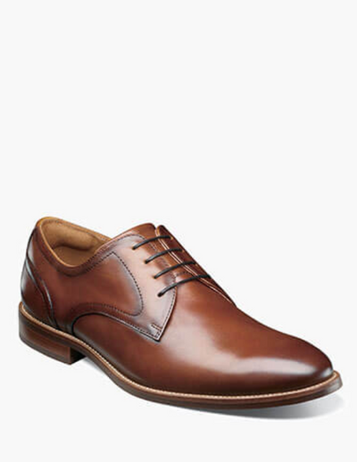 The Florsheim Rucci Plain Toe Oxford, a brown leather dress shoe with four eyelet laces and a low heel, is displayed on a white background—a timeless men's footwear choice from Florsheim.