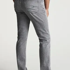 A person is seen from behind wearing 34 Heritage Courage Jeans Urban by 34 Heritage—light gray, straight-leg jeans crafted from premium Urban denim, featuring visible back pockets and stitching details against a plain background.