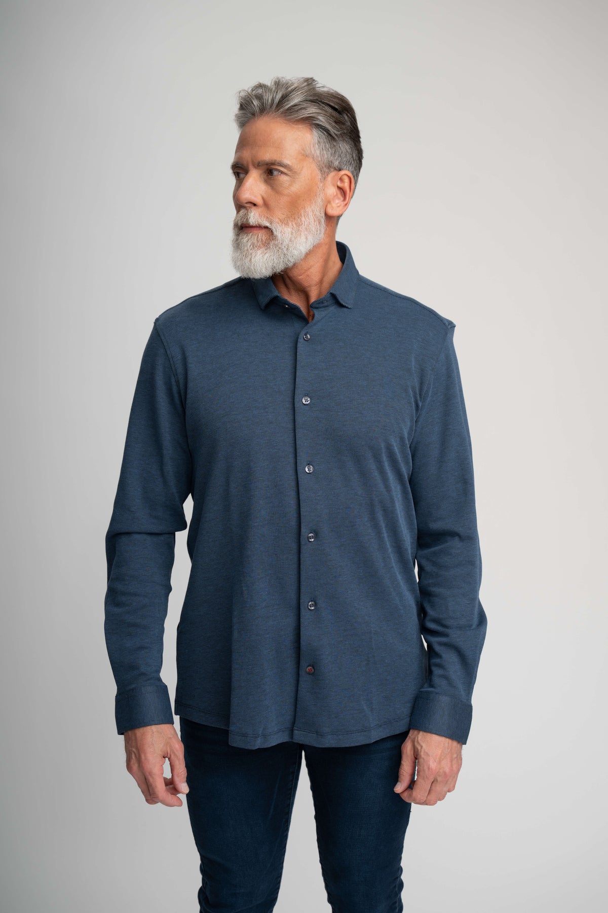 A man wearing a dark blue Stone Rose ORIGIN - Long Sleeve Tech Pique Shirt with a collar.