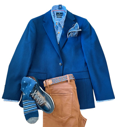 The Giles & Jasper Cashmere Sport Coat by Giles & Jasper, a men's luxury blue blazer in 100% cashmere, is styled with a blue dress shirt, patterned pocket square, brown pants, blue leather shoes, patterned belt, and striped socks on a white background.