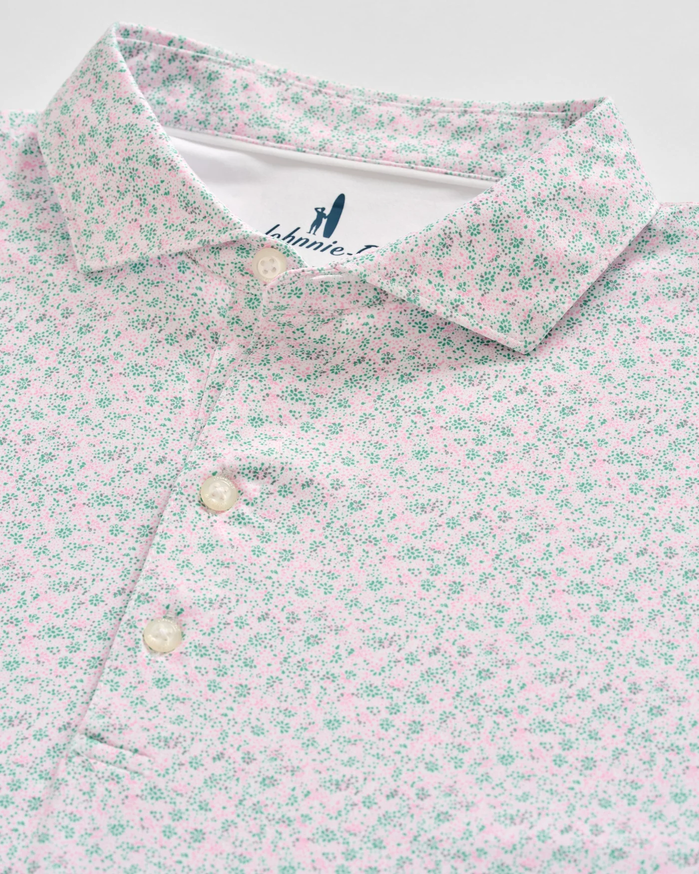A close-up of the Johnnie-O Marietta Big & Tall Knit Polo, featuring a collared design with small pink and green floral print, three buttons, and the signature Johnnie-O label—crafted for featherweight comfort.