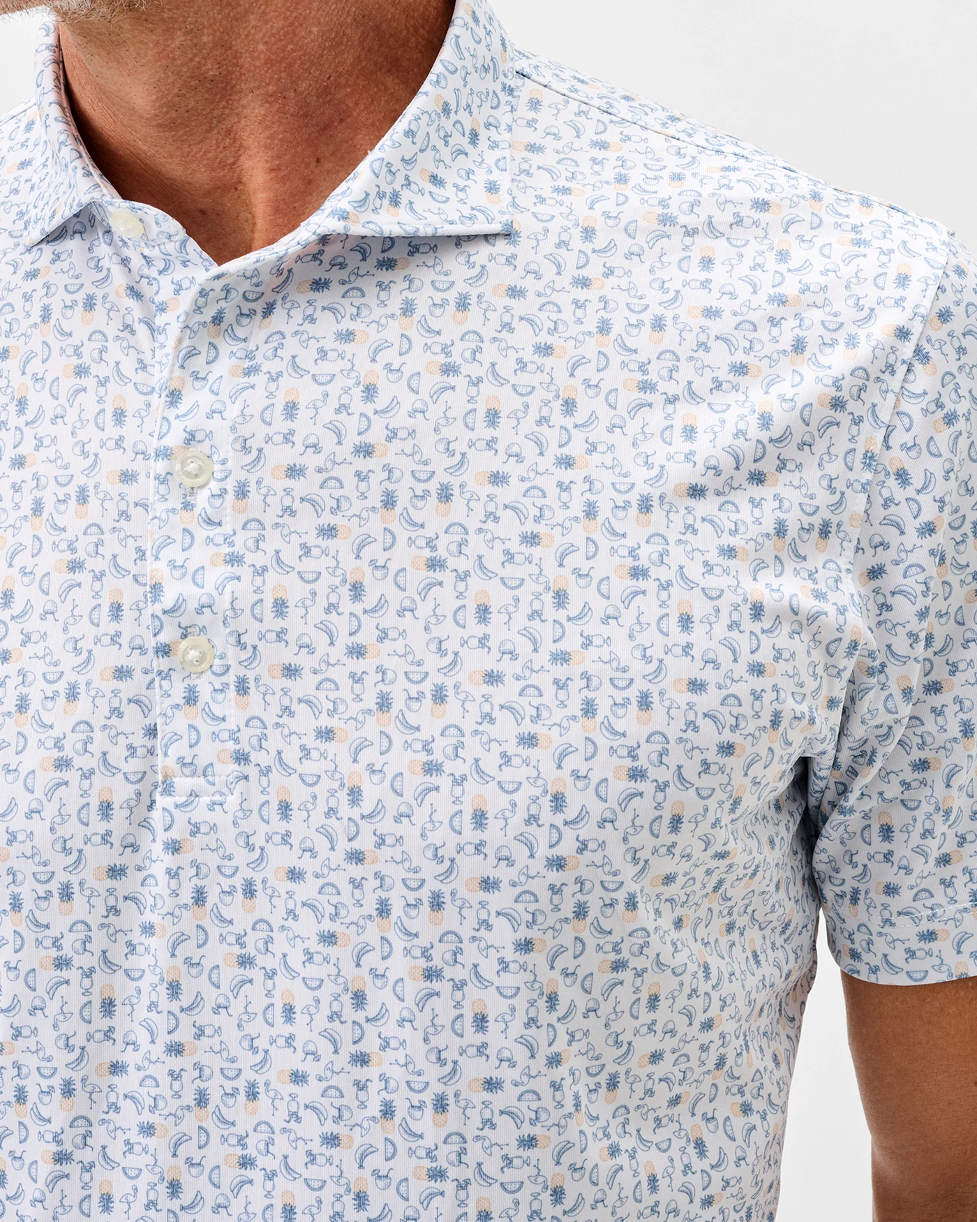 Man wearing the Johnnie-O Cabana Bar Performance Jersey Polo, a soft knit short sleeve shirt from Johnnie-O featuring a light blue and orange geometric floral pattern.