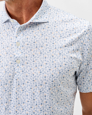 Man wearing the Johnnie-O Cabana Bar Performance Jersey Polo, a soft knit short sleeve shirt from Johnnie-O featuring a light blue and orange geometric floral pattern.