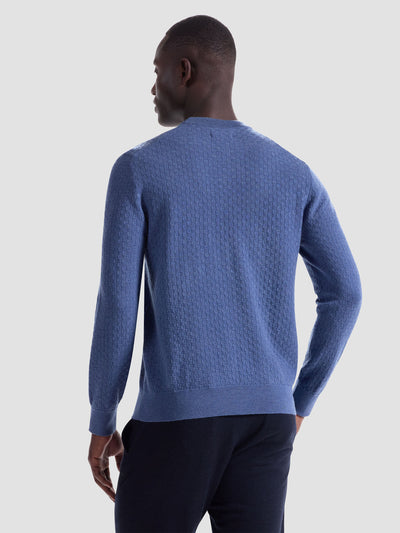 A man faces away from the camera, wearing the Bugatchi Basketweave Crew Neck Sweater HH202CN1 in blue with dark pants, set against a plain light background.