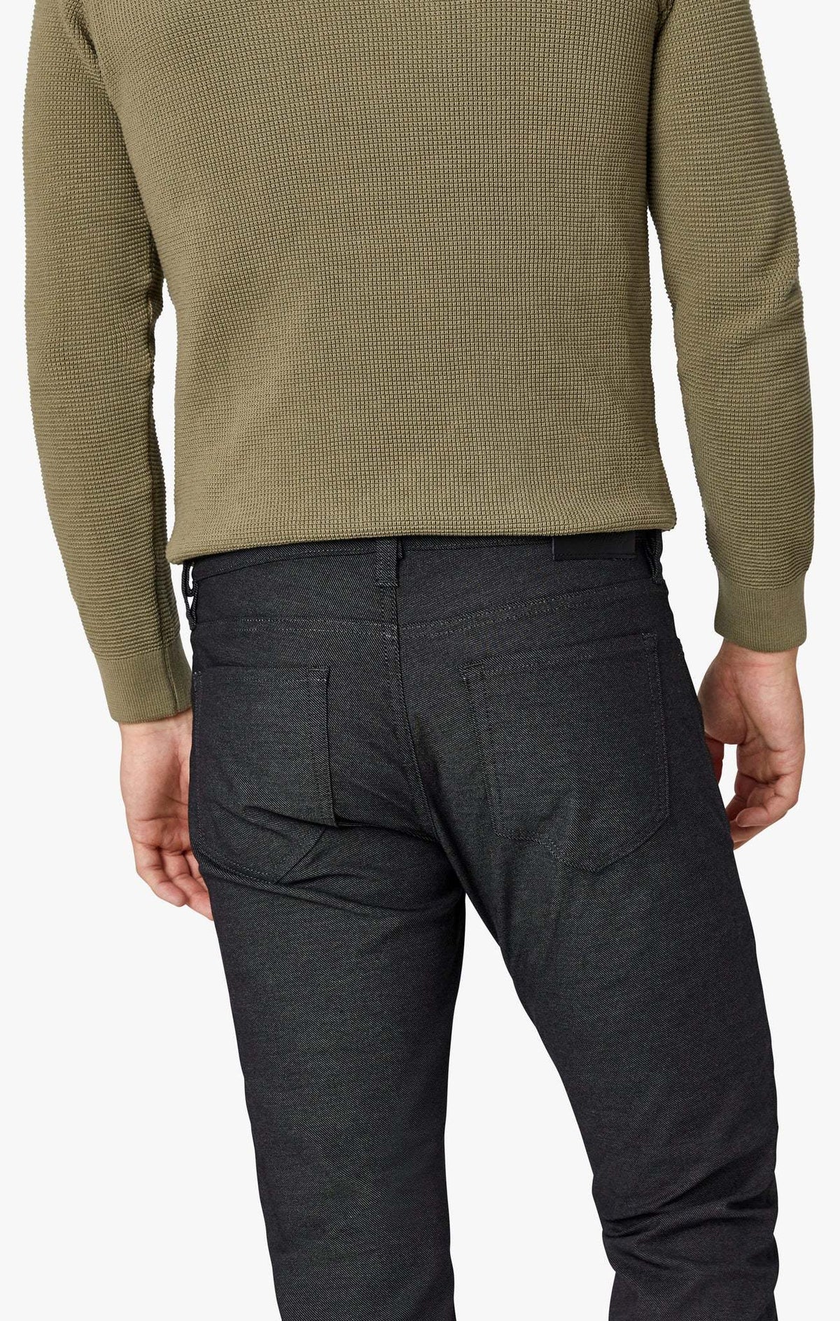 Rear view of a person wearing a green long-sleeved sweater and 34 Heritage Courage Coolmax dark gray modern straight leg jeans.