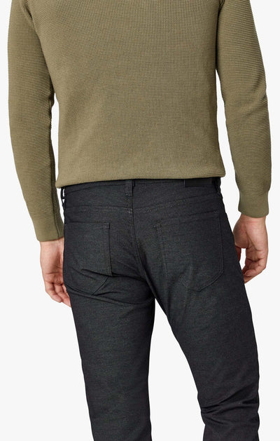 Rear view of a person wearing a green long-sleeved sweater and 34 Heritage Courage Coolmax dark gray modern straight leg jeans.