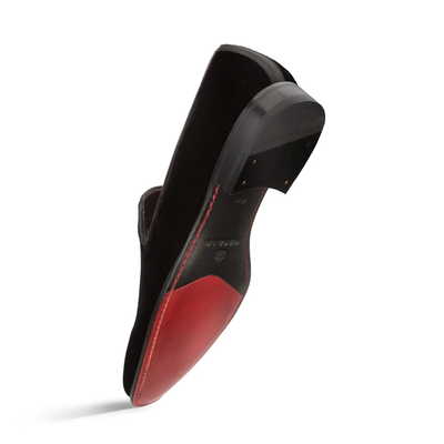 The Mezlan Lublin Velvet Loafer by Mezlan is a men’s dress shoe with a striking red sole, stitched detailing, and a black heel accented with nails. This formal slip-on combines elegance and sophistication.