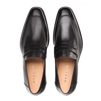Top view of a pair of black calfskin leather loafers with tan insoles, featuring the Mezlan Calfskin Penny Loafer E20243 branding inside—exquisitely handcrafted by Mezlan for timeless sophistication in men’s footwear.