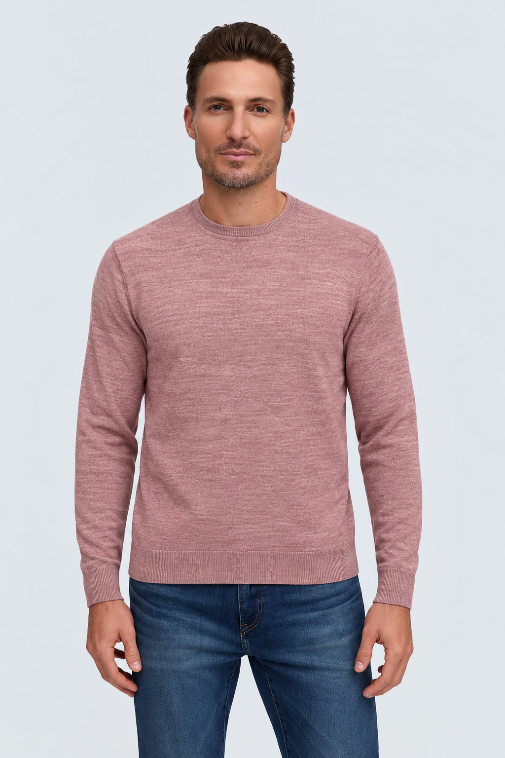 A man wears a dusty rose Raffi Merino Classic Crew Neck Sweater - The Alfie - HWC19392 and blue jeans, showcasing fine Italian yarn craftsmanship.