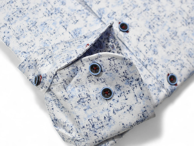Close-up of the Marcello Sky Abstract Sport Shirt OP W131 by Marcello, a white dress shirt with an abstract blue pattern, blue buttons on the cuff and placket, and a refined one-piece collar.