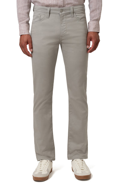 A person models 34 Heritage Charisma Coolmax Big & Tall Jeans by 34 Heritage—light gray, sweat-wicking denim—paired with a light shirt and white sneakers against a white background.