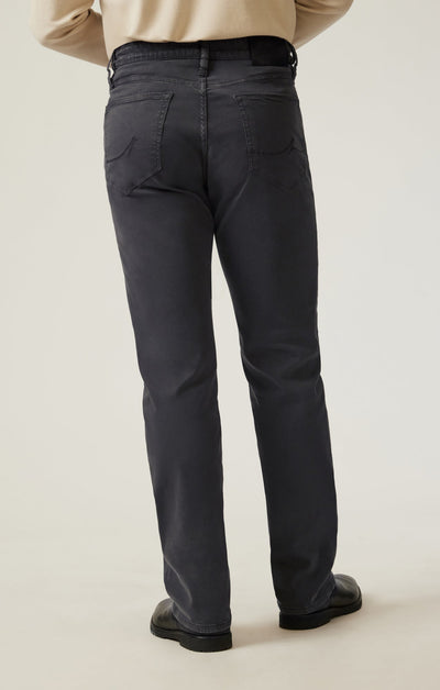 Model wearing 34 Heritage Ash Twill straight leg trousers by 34 Heritage with black shoes and a beige top, shown from the back in a studio with a neutral background.
