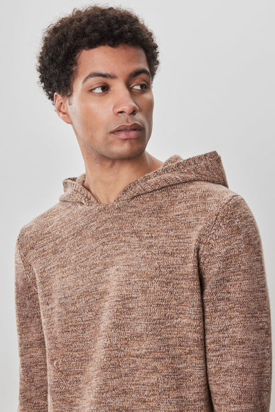 A person with short curly hair wears the Robert Barakett Wildman Sweater in brown, looking to the side against a plain light backdrop.