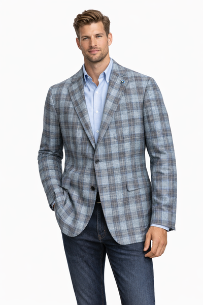 A man wears the Hart Schaffner Marx NY Sports Coat Blue Plaid 36F0083 over a light blue shirt and dark jeans, standing with one hand in his pocket against a plain white background.