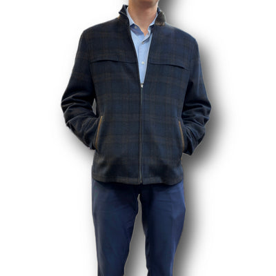 A man models the Enzo Coat Play zip-up jacket by Enzo, styled over a light blue collared shirt and navy pants, with hands in pockets against a white background—a modern twist on luxury outerwear.
