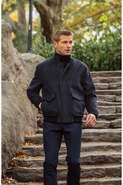 A man wearing a black turtleneck and a Hart Schaffner Marx Genesee Plaid Wool Jacket walks down stone steps.