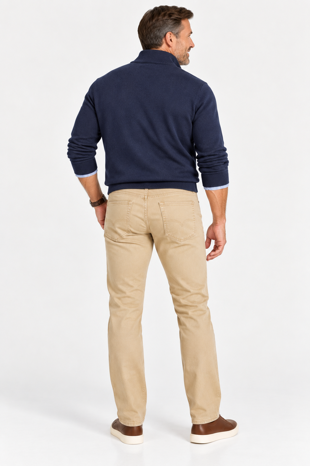 A man seen from behind wearing a navy blue quarter-zip sweater, Alberto Pipe 1984 Stretch Denim tan trousers, and brown sneakers.