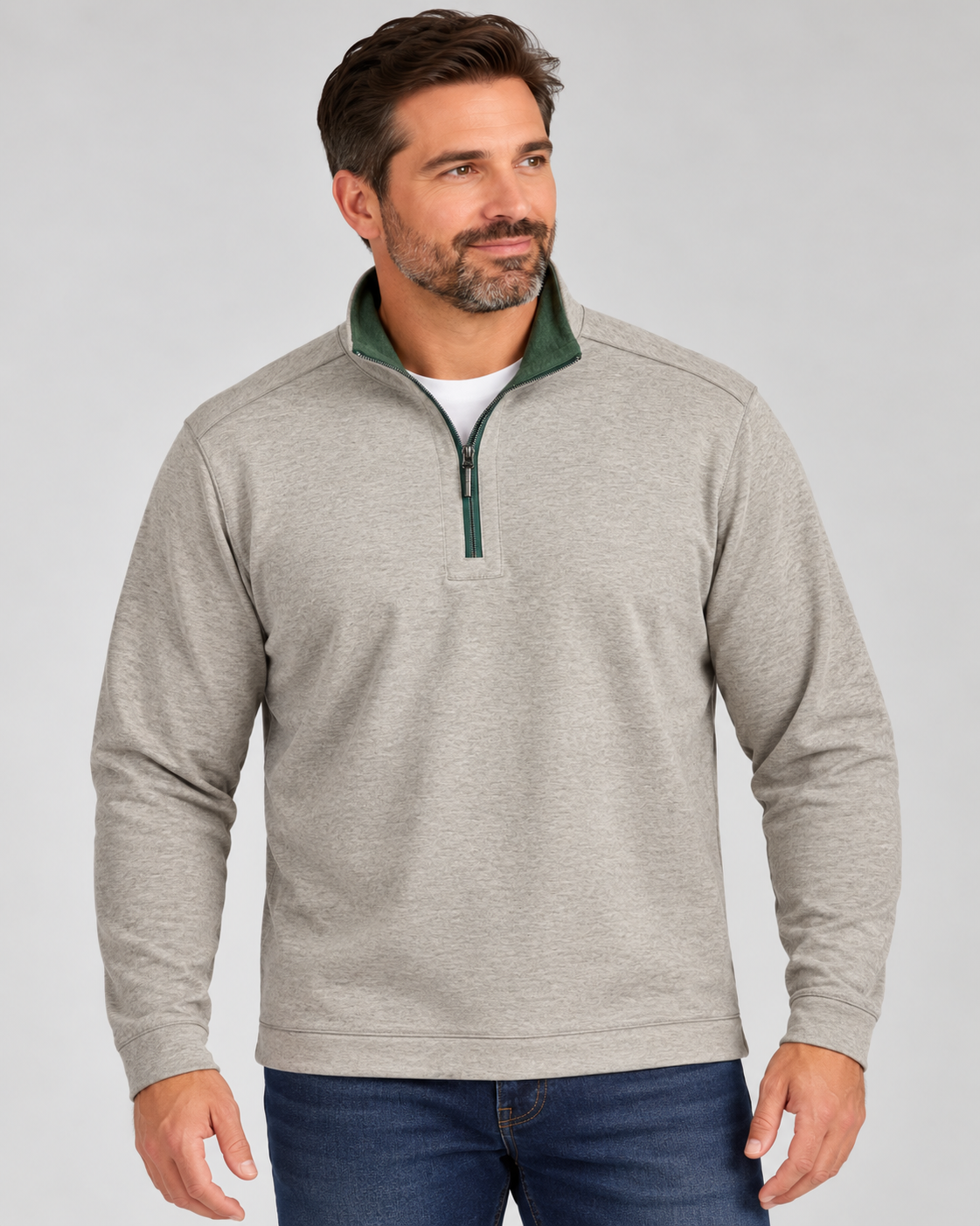 Man wearing a light gray Tommy Bahama Flipview 1/2 Zip Reversible Sweatshirt with a dark green inner collar over a white t-shirt and blue jeans.