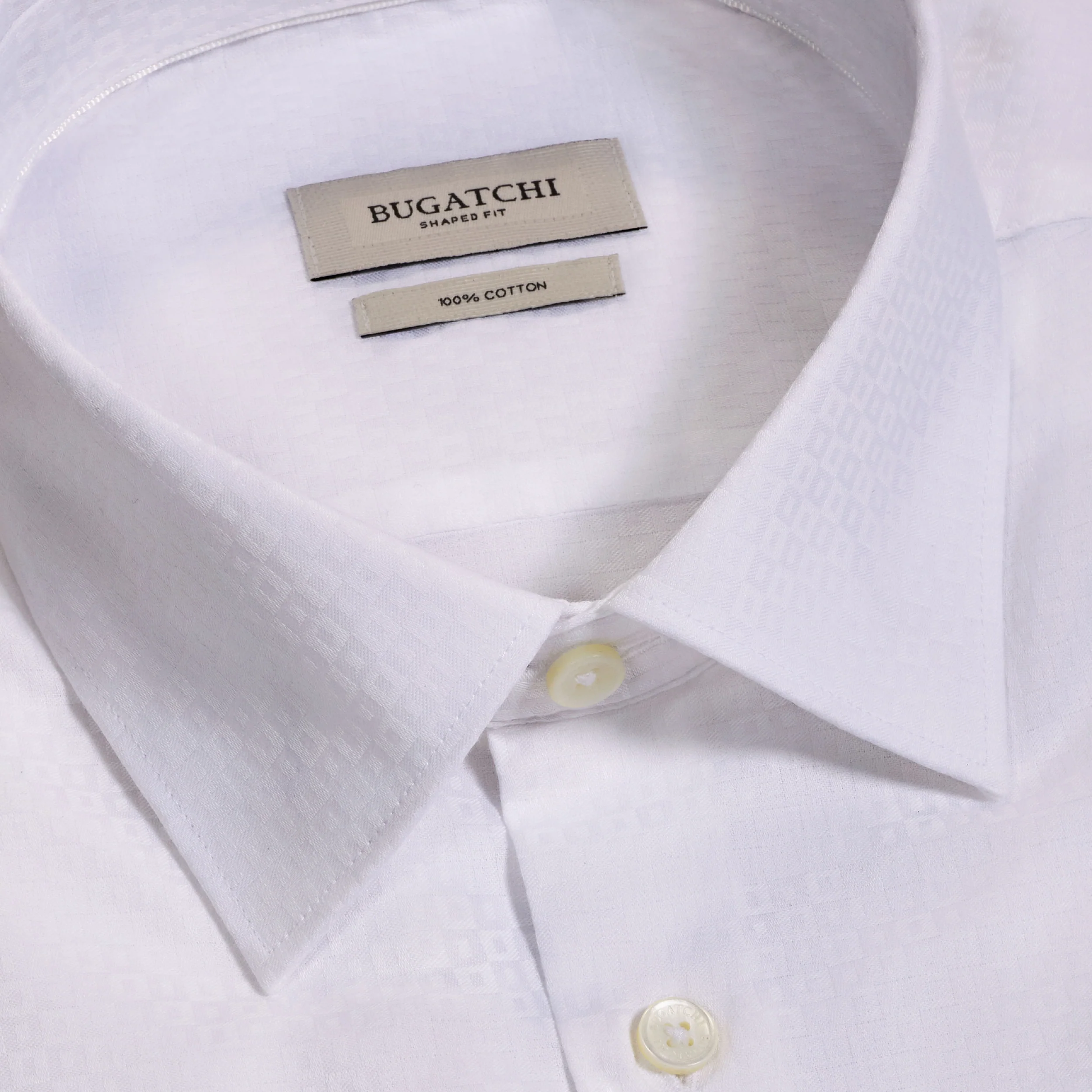 Close-up of the Bugatchi Julian Tonal Geometric Jacquard Shirt KS4001L3S in white, featuring a pointed collar, white buttons, and an interior label reading “Bugatchi Shaped Fit 100% Cotton”; this men’s shirt showcases a subtle geometric print and is wrinkle resistant to maintain a crisp appearance.