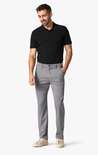 Man wearing 34 Heritage Charisma Shark Twill Big & Tall pants and a black polo shirt stands against a plain white background with one hand in his pocket.