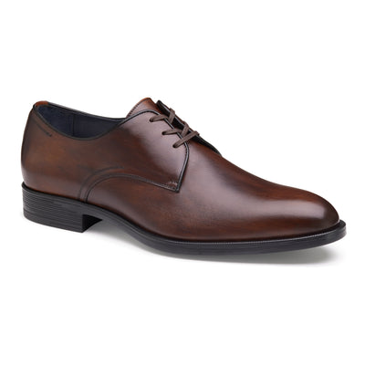 The Johnston & Murphy Flynch Plain is a brown leather dress shoe with Italian hand-stained uppers, black laces, a low black heel, and a rounded toe, shown against a white background.