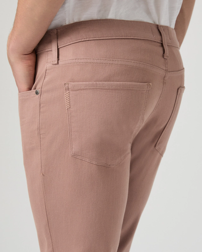 A person shown from the waist down with one hand in their pocket wears Paige Federal Slim Straight Jeans in light pink paired with a white shirt—showcasing a modern men’s jeans look by Paige.