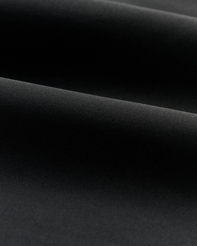 Close-up of the Johnnie-O Motion Big & Tall 1/4 Zip Swtr’s smooth black fabric with gentle folds, highlighting the soft lighting and subtle shadows from this moisture-wicking quarter zip by Johnnie-O.
