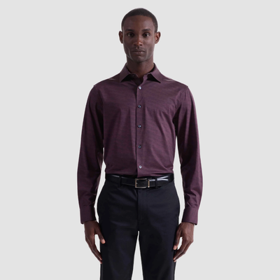 A man stands facing forward, wearing the Bugatchi James Herringbone Sport Shirt HF9508K60 by Bugatchi, paired with black pants and a black belt, against a plain light gray background.