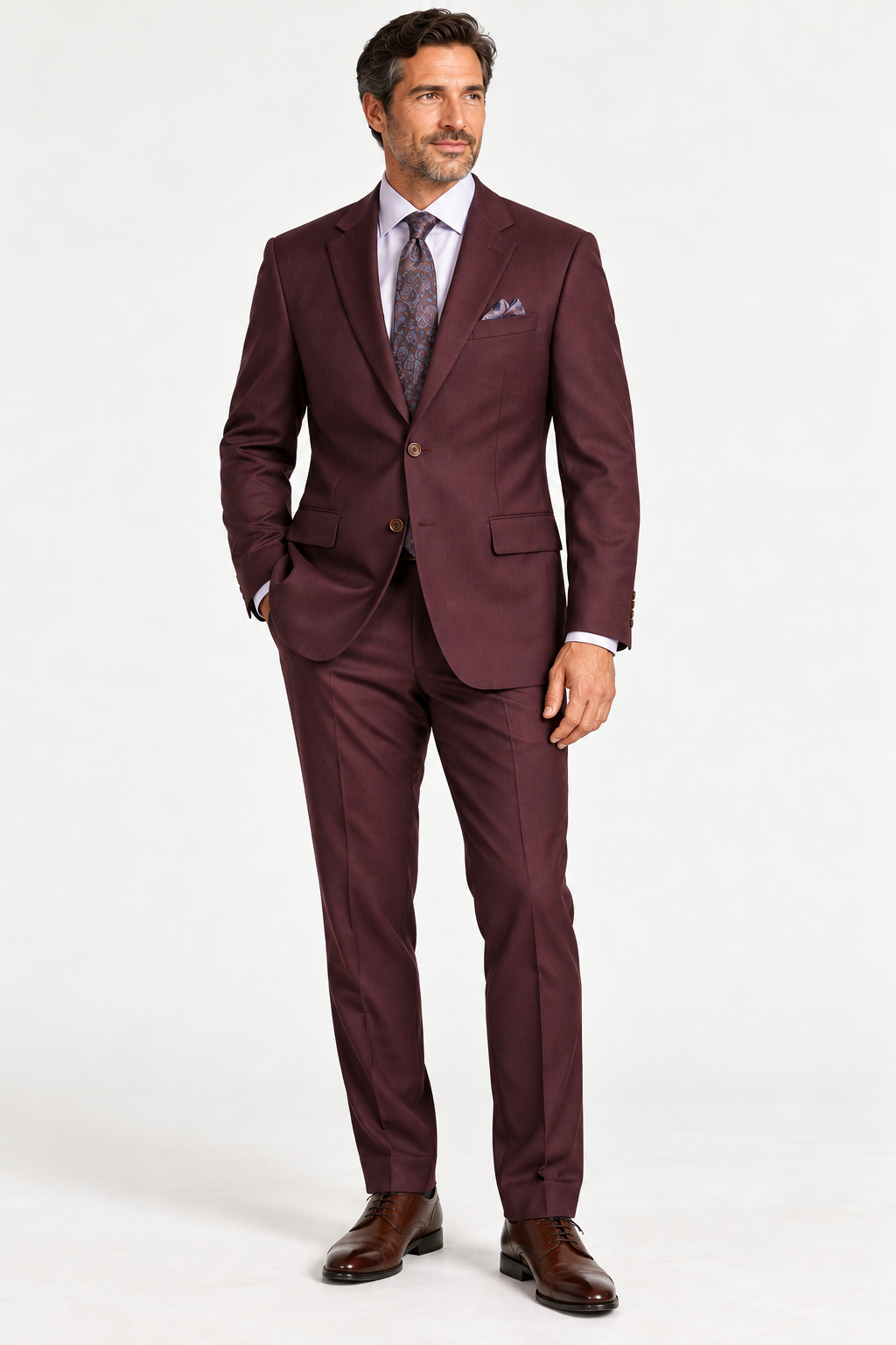 A man wearing a MaxDavoli Men’s Burgundy Wool Suit MD2800, a light shirt, a patterned tie, a pocket square, and brown dress shoes.