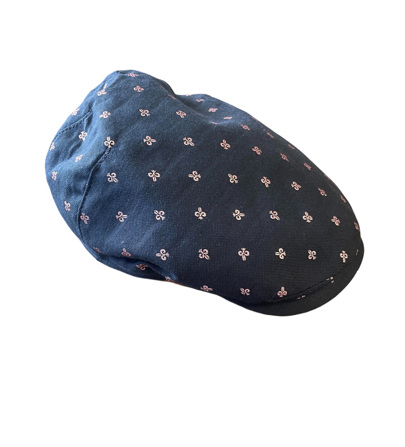 The Wigens Cap 101414 by Wigens is a navy cap featuring small, evenly spaced white and pink floral patterns reminiscent of fleur de lis, shown on a white background.
