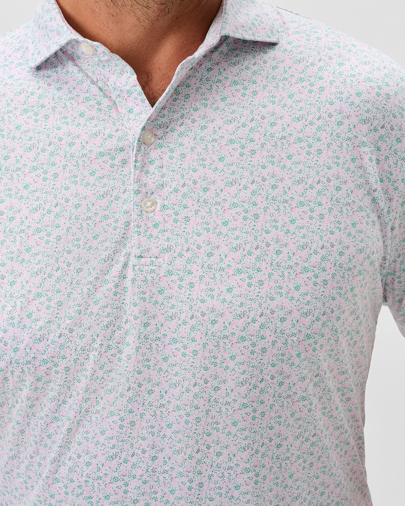 Close-up of a person wearing the Johnnie-O Marietta Big & Tall Knit Polo, a light, featherweight shirt with a small floral print, three-button collar, and UPF 50 sun protection for comfort and style by Johnnie-O.