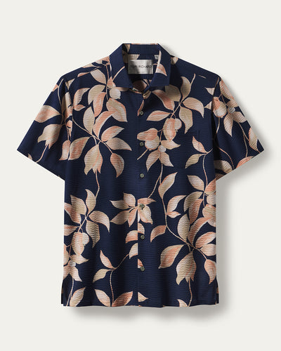 Discover the Tori Richard Textured Fresco De Cas Shirt 1956M0387—a short-sleeve button-up featuring a navy blue background with peach, beige, and light brown leafy floral designs, crafted from breathable cotton pucker lawn and proudly made in Hawaii by Tori Richard.