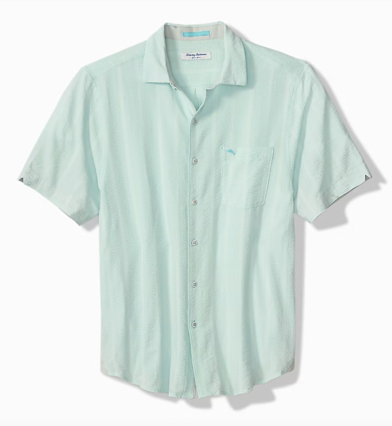 The Tommy Bahama Nova Wave Short Sleeve Shirt by Tommy Bahama features light blue fabric, contrast stitching, a front pocket, and short sleeves, shown on a white background.