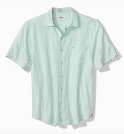 The Tommy Bahama Nova Wave Short Sleeve Shirt by Tommy Bahama features light blue fabric, contrast stitching, a front pocket, and short sleeves, shown on a white background.