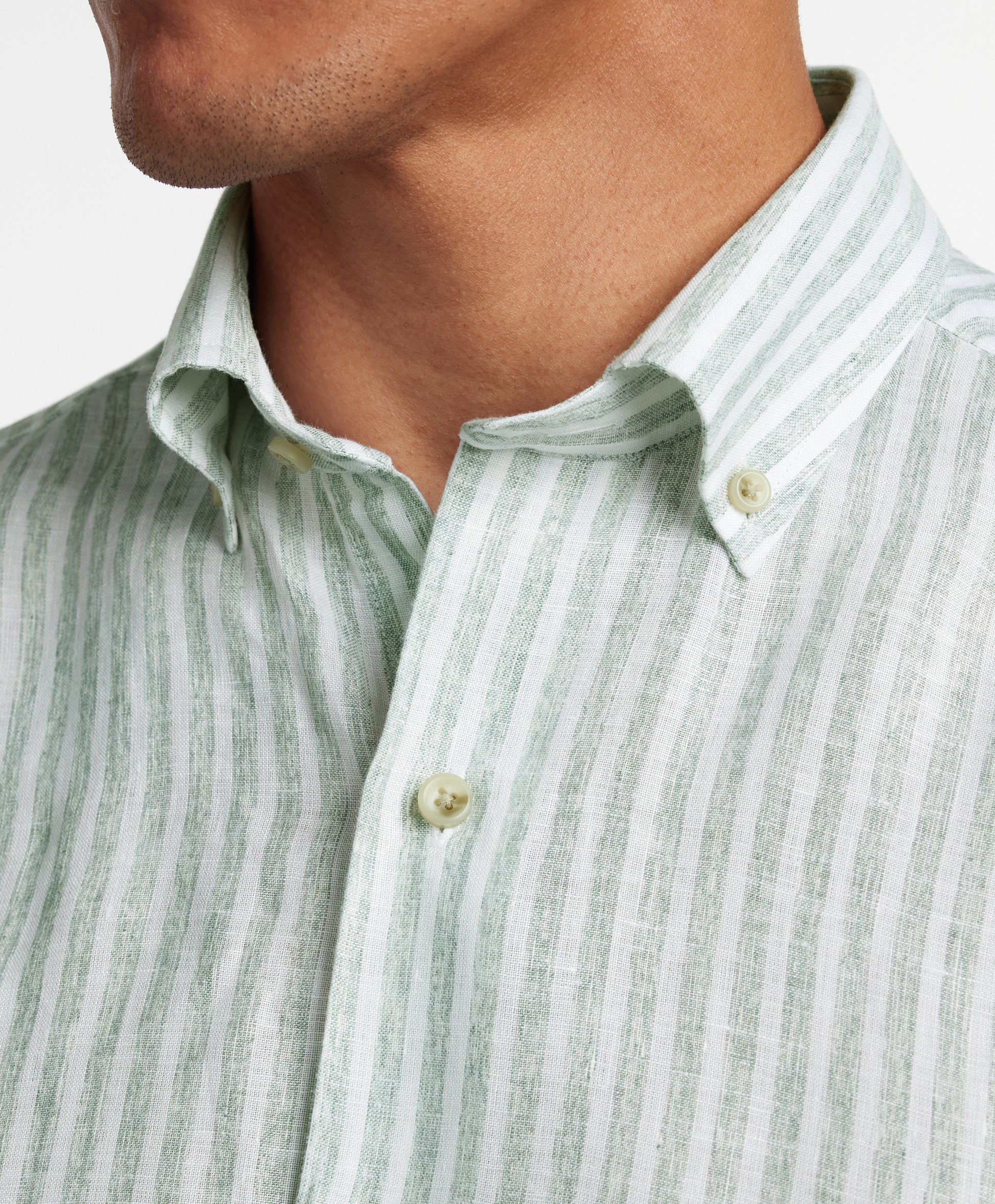 A close-up of a person wearing the David Donahue Linen Stripe Sport Shirt (CBBD12955335) featuring sage and white stripes in a classic button-down style.